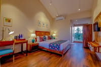 A garden-facing room at Ananyamaya with a desk and balcony