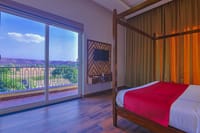 A room at Ananyamaya with the window onto the plain and the hills beyond