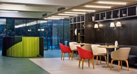 Restaurant seating beside the lime-green spiral staircase and glass wall