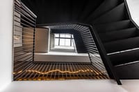 Black steel stairwell atrium with lit signage and arched window