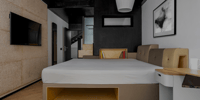 Guest room with cork-panelled walls, platform bed and pendant light