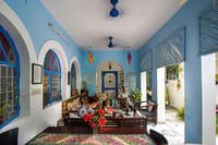 Blue-walled lounge with arched openings, rugs and family seating