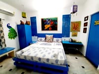 Art-themed bedroom in blue with Indian paintings and a peacock figure