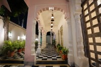 Pink scalloped arches and lanterns along the entrance arcade at Dev Mahal, Jaipur