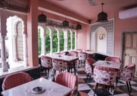 Pink arches and floral chairs in the rooftop restaurant at Dev Mahal, Jaipur