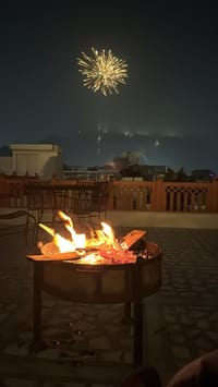 Rooftop bonfire at night with fireworks over the old city