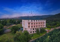 Aerial view of the resort building against Aravalli hills with birds overhead