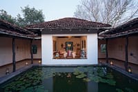 Open-sided dining pavilion beside a lantern-lit lily pond at dusk at Samode Safari Lodge, Bandhavgarh
