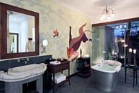 Villa bathroom with freestanding tub, carved stone basin and hand-painted animal mural at Samode Safari Lodge, Bandhavgarh