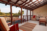 Villa private deck with day-bed, rustic timber pergola and striped rugs overlooking the landscape at Samode Safari Lodge, Bandhavgarh
