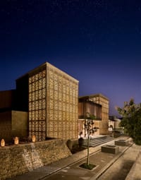 Lodge entrance flanked by tall lantern-lit jali screen towers under a starry sky at Aramness, Sasan Gir