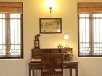 Writing desk with lamp and framed watercolour between two windows at Irai Safari Retreat, Tadoba