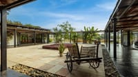 Paved central courtyard with a wooden bullock cart and planted beds at Bori Safari Lodge, Satpura