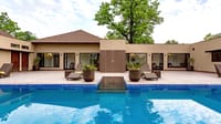 Blue-tiled swimming pool with loungers and rooms around the terrace at Bagh Villas, Kanha