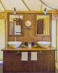 Tented Suite — woven-cane vanity with twin white basins and mirrors under canvas at Bagh Villas, Kanha