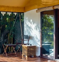 Tented Suite — campaign chair and cane table on the verandah beside bamboo at Bagh Villas, Kanha