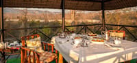 Breakfast with silver teapots on a covered machan deck overlooking the riverbed and forest at Jim's Jungle Retreat, Corbett