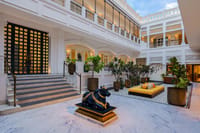 White open-air courtyard with marble steps, Nandi statue and yellow daybed at Pilibhit House, Haridwar
