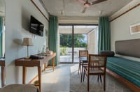 Arundhati suite sitting room with striped day bed, cane chairs and doors to a private terrace at Amrit Bhawan, Haridwar