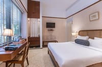 Kratu bedroom with cane headboard, writing desk by the window and terrazzo floor at Amrit Bhawan, Haridwar