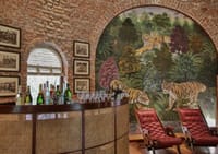 Safari Club bar with cane counter, tiger mural and red leather chairs at Jaagir Manor, Dudhwa