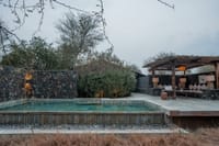 The Pool Villa private pool with stone walls and shaded pergola seating area at The Blackbuck Lodge, Velavadar