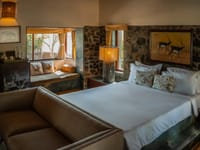 The Villa bedroom with cushioned window seat, butterfly cushions and stone walls at The Blackbuck Lodge, Velavadar