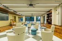 Riverside lounge with armchairs, chequered floor and glass walls facing the Ganga at Ekaanta, Haridwar