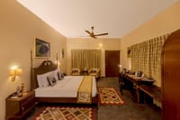 The Wildernest — four-poster bed with gold runner, kilim rugs and writing desk at Singinawa Jungle Lodge, Kanha