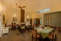 The Wildernest — lounge and dining room with fireplace and wildlife photographs at Singinawa Jungle Lodge, Kanha
