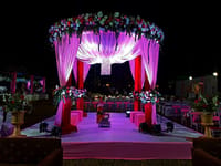 Flower-decked wedding mandap lit pink on the lawns at night at WelcomHeritage Tadoba Vanya Villas, Tadoba