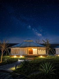 Safari-style tent at WelcomHeritage Tadoba Vanya Villas lit warmly at night under a starry sky