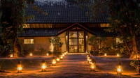 Lantern-lit path leading to the lodge entrance at dusk at Tiger Tops Tharu Lodge, Chitwan
