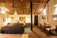 Traditional Room with a double bed, woven reed ceiling and safari chairs at Tiger Tops Tharu Lodge, Chitwan