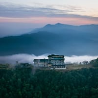 Aerial view of the lodge on a forested ridge above clouds at dusk at Sarangkot Mountain Lodge, Pokhara