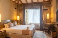Suites bedroom with a king bed and a bathtub set into the window alcove at Sarangkot Mountain Lodge, Pokhara