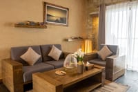 Suites living room with timber sofas, cushions and fresh lilies at Sarangkot Mountain Lodge, Pokhara