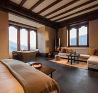 Bhutanese Farmhouse Suite with a bed, freestanding bathtub by the window, wood-burning stove and sofa at Gangtey Lodge, Gangtey