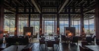 Main lodge lounge and dining room with twin stone fireplaces and floor-to-ceiling valley views at Gangtey Lodge, Gangtey