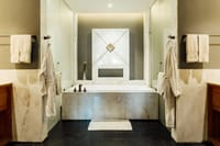 Terrace Room marble bathroom with a bathtub, robes and towels at Bhutan Spirit Sanctuary, Paro