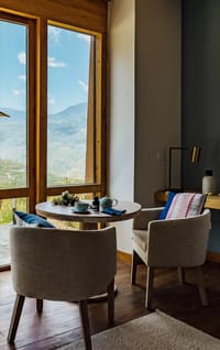 Terrace Room tea table and armchairs beside a picture window with valley views at Bhutan Spirit Sanctuary, Paro