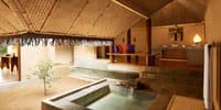 Open-air bathroom with sunken stone bath, lily pond and twin basins under woven ceilings at Jetwing Vil Uyana, Sigiriya