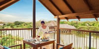 Staff setting a private dining table on a covered tree-house deck above the wetlands at Jetwing Vil Uyana, Sigiriya