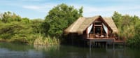 Water Dwelling on stilts with thatched roof, deck and sun loungers above the lake at Jetwing Vil Uyana, Sigiriya