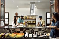 Breakfast counter laid with fresh fruit and juices in front of the open kitchen at Svatma, Thanjavur