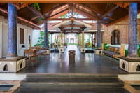 Pillared courtyard pavilion with blue stone columns, wooden benches and polished dark floor at Svatma, Thanjavur
