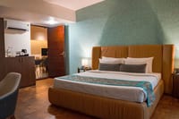 Shambhala villa bedroom with tan upholstered bed against a turquoise textured wall at Java Rain Resort, Chikmagalur