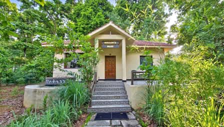 A cottage at Tathastu Kanha, steps up to its porch among the trees