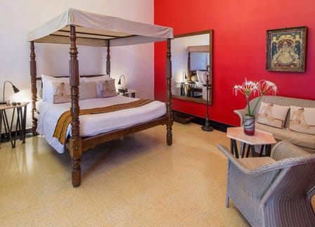 Roof Garden Suite at The Malabar House with a four-poster bed, red wall and wicker seating