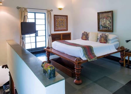 Upstairs bedroom of The Malabar Suite at The Malabar House with a carved wooden bed and black stone floor